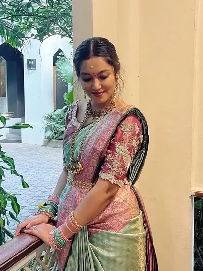 This bride looks absolutely stunning in her pastel green and pink saree. The custom-designed blouse with intricate bird and floral embroidery adds a whimsical and personal touch to her engagement look.