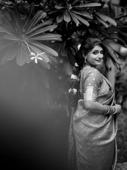 A timeless black and white bridal portrait of Apeksha, looking over her shoulder with a gentle smile.
