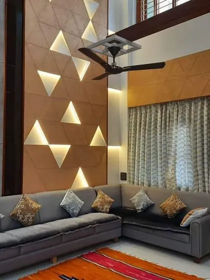 A double-height living room with a dramatic accent wall featuring backlit triangular panels. This design uses vertical space to create a sense of grandeur.