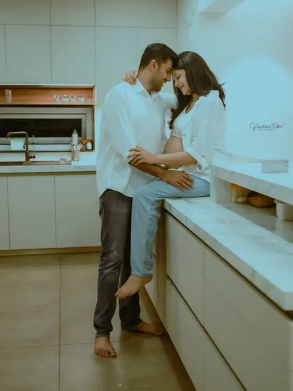 A romantic shot of a couple in their kitchen, capturing the everyday intimacy and love as they await their baby's arrival.