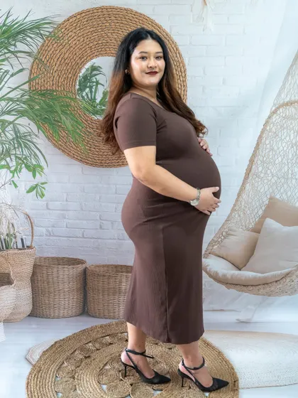 A simple and elegant side-profile shot of a mom-to-be in a brown dress, taken in our boho studio.