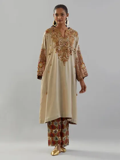 An elegant beige kurta with a heavily embroidered yoke and sleeves. Paired with printed pants, this look is a beautiful blend of intricate craftsmanship and modern styling.