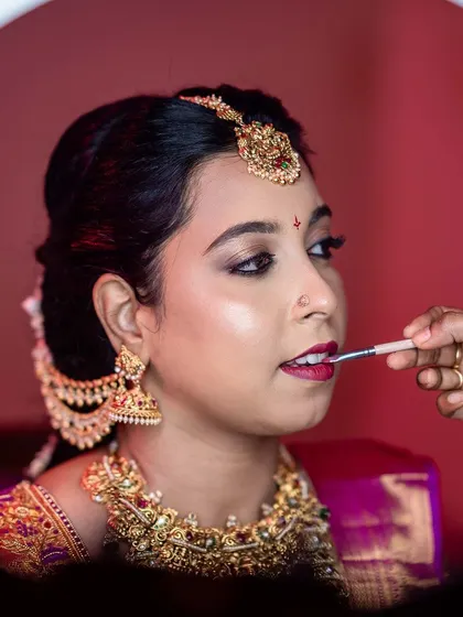 A behind-the-scenes shot of the final touch-up on the lips, framed by a ring light. This shows the precision and care that goes into every look.
