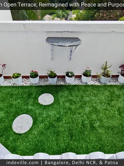 An overhead view of a simple yet effective terrace garden patch. The combination of green turf, white pebbles, and round stepping stones creates a neat and low-maintenance green area.