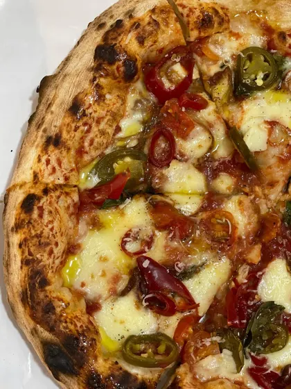A spicy pizza with pickled red and green chilies. The vibrant colors and promise of heat make this a very popular choice.
