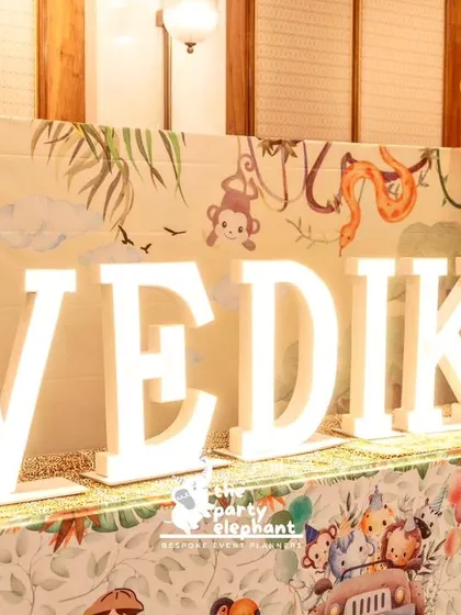 Large, light-up marquee letters spelling 'VEDIKA' were placed on a table with a custom safari-print tablecloth, creating a bold and personalized statement piece.