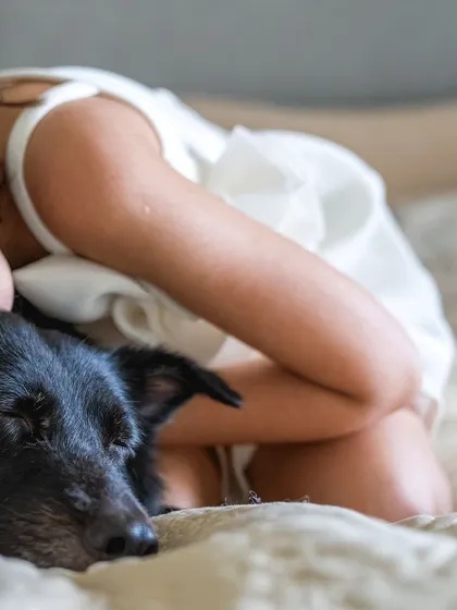 A quiet, sleepy moment between a girl and her dog on the bed.
