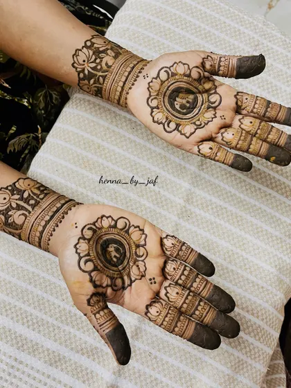 A beautiful bridal design with a central floral mandala on each palm. The fingers are decorated with simple bands and the wrists have a wide, detailed floral cuff.