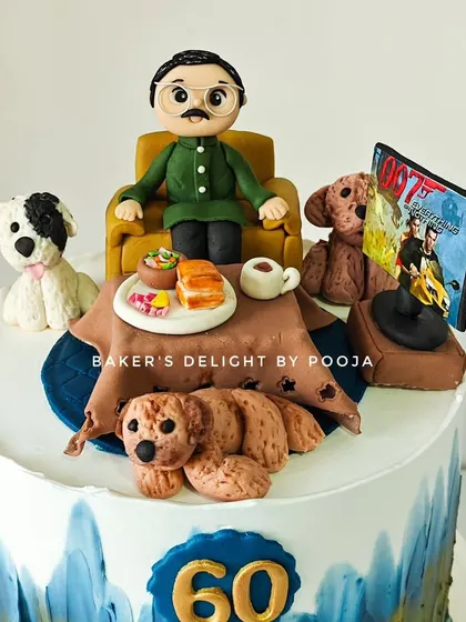 This two-tier cake for a 60th birthday features a detailed scene with a custom figurine of the birthday dad, his three dogs, and his favorite things: chai, misal pav, and action movies.