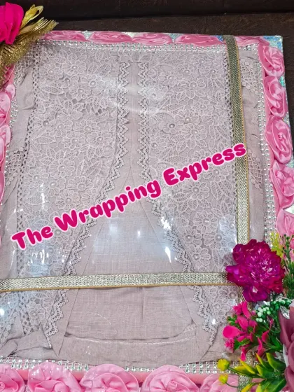 A delicate lace suit packed in a box decorated with pink fabric roses. The color coordination makes the packing look very sophisticated.