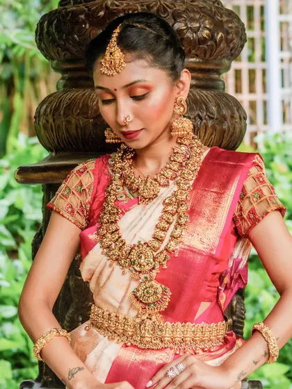 A detailed close-up of our antique-finish temple jewellery. You can see the craftsmanship in the necklace, jhumkas, and maang tikka.