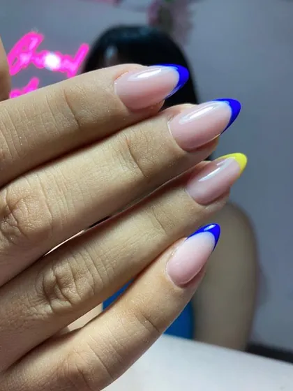 We can customize your French manicure with any color you like. This set features bold blue and yellow tips on almond-shaped extensions.