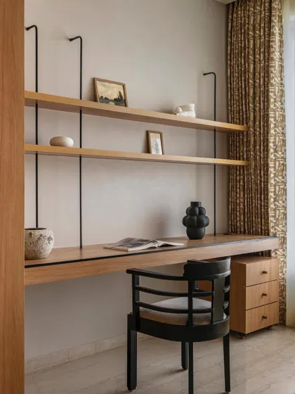 The minimalist study area in Apartment 3201, featuring natural oak shelves and a sleek black chair.