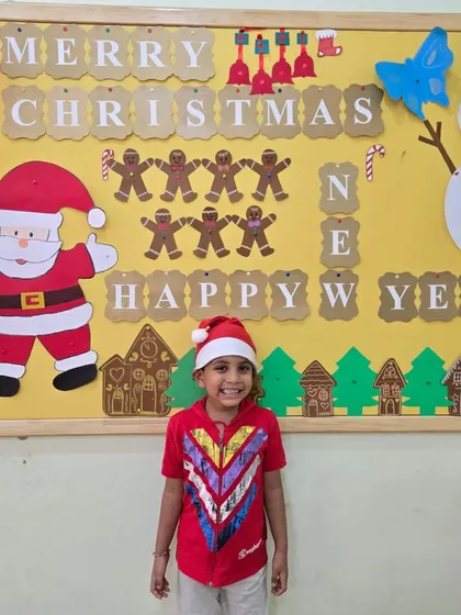 A happy smile in front of our Christmas-themed bulletin board. We create a festive atmosphere where children can learn about different cultural celebrations in a warm and welcoming environment.