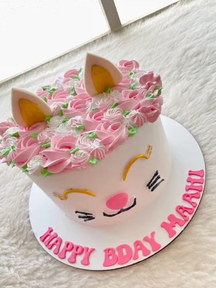 A sweet and simple kitty cat cake. The design uses piped rosettes for the "fur" on top and has cute little ears and a hand-drawn face.
