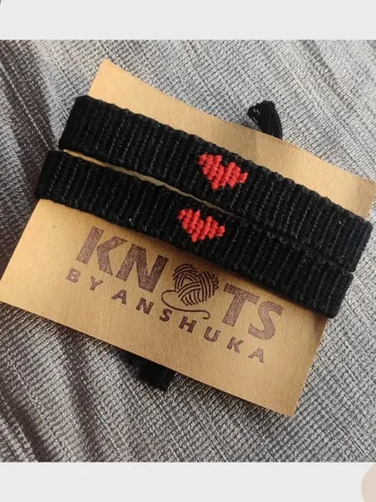 A pair of black friendship bracelets with a simple red heart in the center. It's a subtle and sweet way to have a matching set.