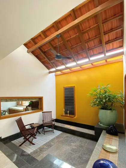 This semi-open seating area is illuminated by a long skylight set into the traditional tiled roof. The design allows for abundant natural light while protecting from the elements, creating a perfect transitional space.