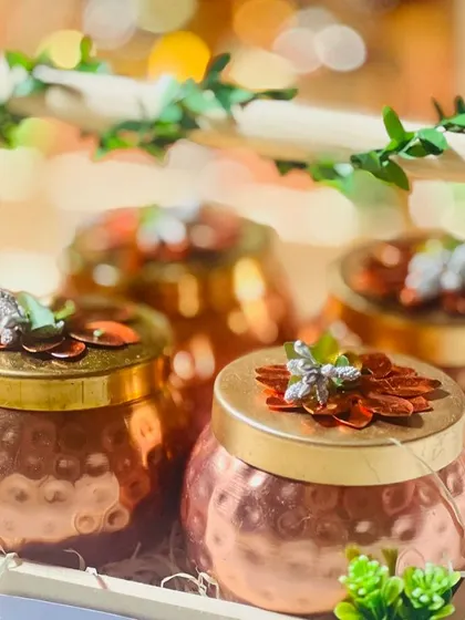 A close-up of a premium gift featuring hammered copper jars with decorative lids, arranged in a wooden crate with faux ivy.