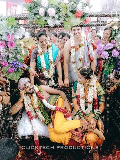 A fun, candid moment from a wedding ceremony, with the groom playfully relaxing as family members surround the couple with smiles.