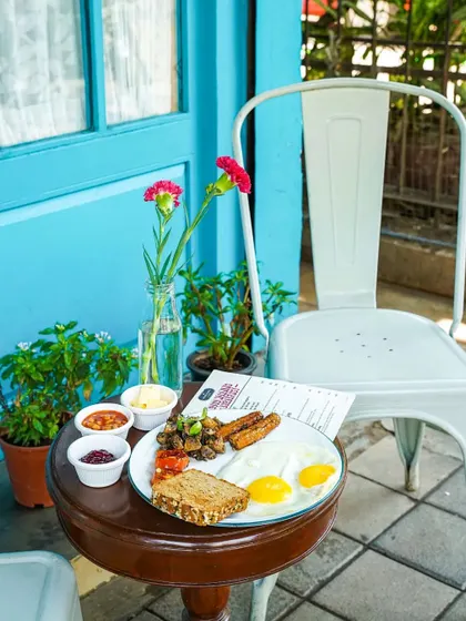 A classic English breakfast plate set on a small table outside a charming cafe with a blue door. This shot creates a serene and inviting atmosphere for a relaxed morning meal.