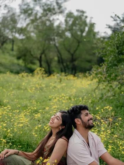A wide shot of the couple enjoying a laugh in the field. It highlights the vast, beautiful landscape that becomes a part of their story.