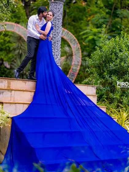 A sweet and romantic moment on the steps, with the groom-to-be stealing a kiss. The incredibly long train of the blue gown creates a stunning visual that fills the frame.