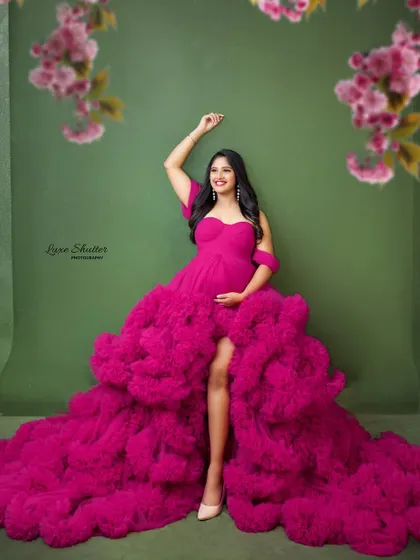 Framed by soft, out-of-focus blossoms, this portrait feels like a dream. The vibrant pink gown stands out beautifully against the muted green backdrop.