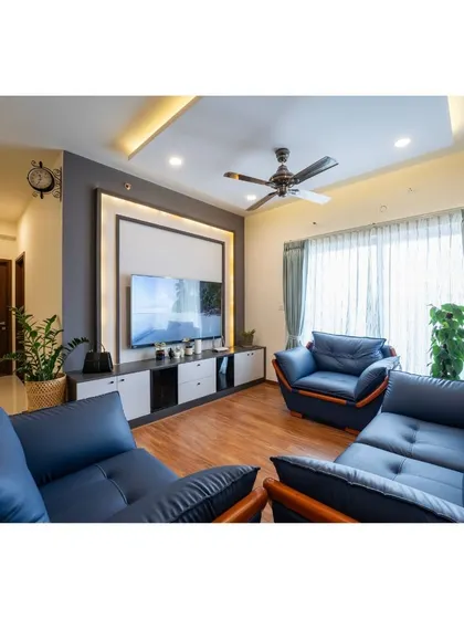 Another view of the living room with blue leather sofas, highlighting the elegant TV wall unit and the natural light filtering through sheer curtains, creating a perfect balance of style and comfort.