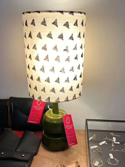 This image from our partner Ethico shows our green 'Barni' lamp. The base is inspired by traditional pickle jars, and the shade features a simple, hand-blocked triangle pattern, creating a modern yet rooted look.