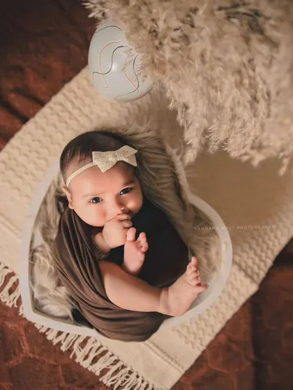 A beautiful, awake moment captured during a newborn session. The baby's direct gaze and tiny hand near their mouth create an engaging and sweet portrait.