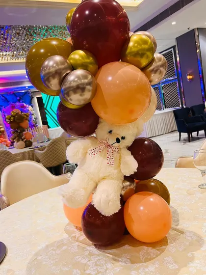 A teddy bear centerpiece for a guest table, using a mix of metallic and matte balloons.