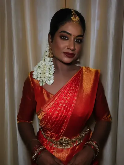 A beautiful portrait of a dusky bride. The makeup is flawless, with a matte finish that looks stunning against her traditional red saree.