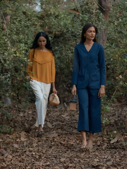 This shot features two models walking together in the woods, creating a story of shared experience. It showcases two different outfits from the collection in a cohesive and natural setting.