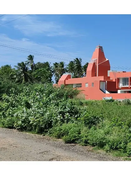 The Sai Temple seen from a distance, rising above the lush green landscape. The form is a contemporary interpretation of a traditional temple silhouette.