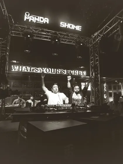 A triumphant moment with DJ Panda at the end of a successful night. Hands in the air, celebrating with the crowd.