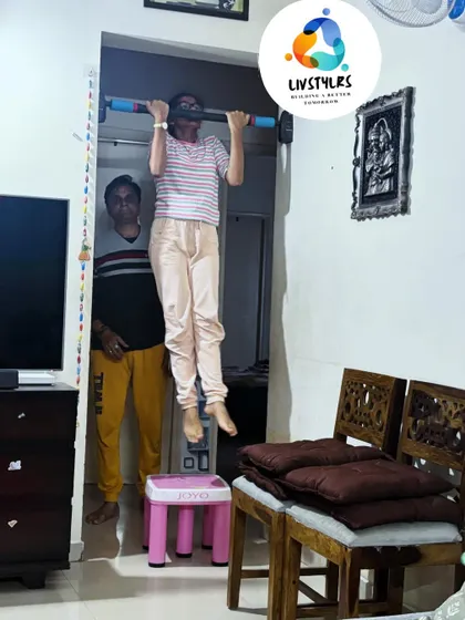 A young girl hangs from a pull-up bar, building upper body strength. I always supervise and assist to make sure the kids are safe and confident.