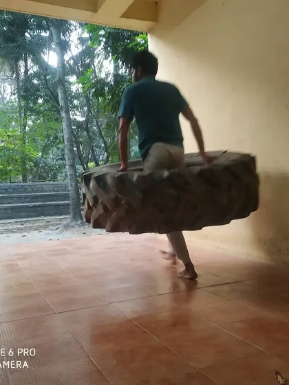 A student carrying the tire, demonstrating the functional strength we build in our classes.