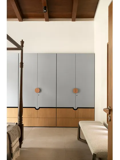 A view from the side of the bed, showing the clean lines of the wardrobe and the simple, upholstered bench.