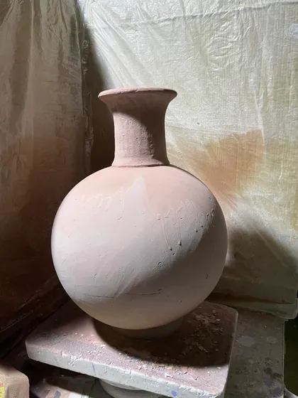 A classic, wheel-thrown terracotta pot. The beauty of this piece is in its simple, balanced form, with a spherical body and a defined neck. It's a timeless shape.