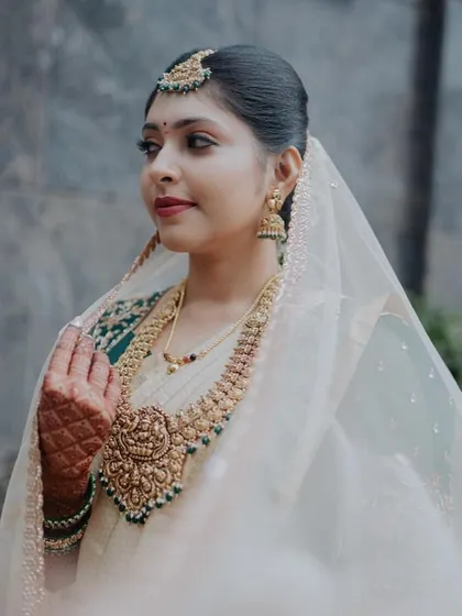 A portrait of our bride who opted for a non-red look, looking ethereal in her off-white saree, green blouse, and sheer veil.