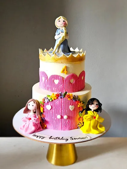 The full view of the two-tier princess castle cake with three handmade princess figurines.