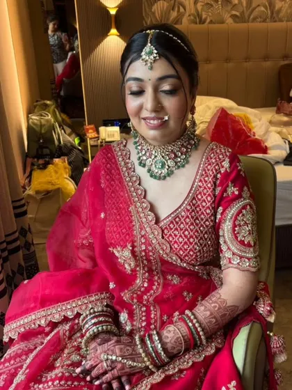 The bride's smile says it all. This look was created to bring out her joy and confidence, with a focus on glowing skin and eyes that sparkle. The pink lehenga and emerald jewelry pair beautifully with the soft glam makeup.