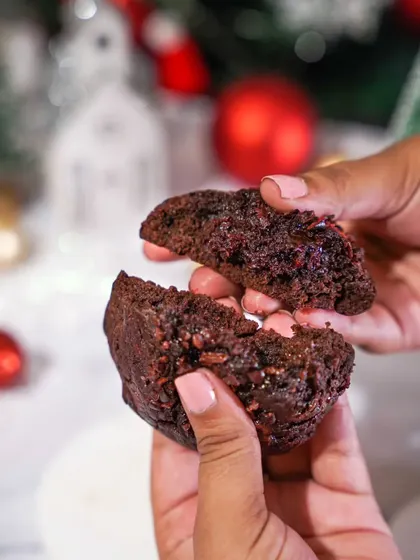 Hands breaking open a gooey, rich chocolate cookie. The close-up on the texture and filling makes this a perfectly tempting shot for a Christmas cookie promotion.