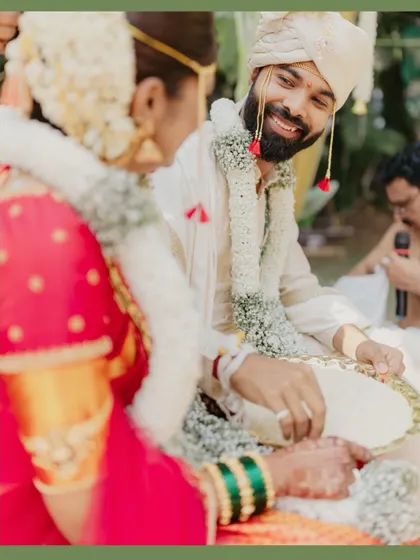 A candid shot of the groom smiling at his bride during a wedding ritual.