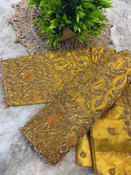 A view of both sleeves of the mustard yellow blouse, laid flat to display the symmetrical and dense embroidery work.
