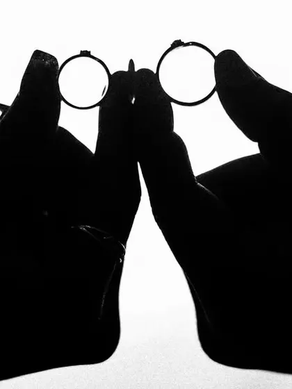 A creative silhouette of a couple holding their rings, forming a pair of glasses. This playful and artistic shot is a unique way to announce an engagement.