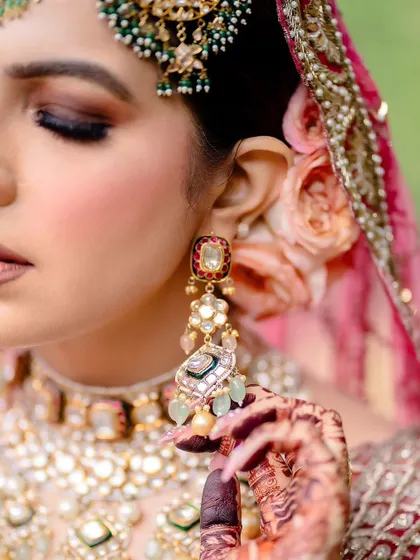 A close-up of the bride's earring and the mehendi on her hand.