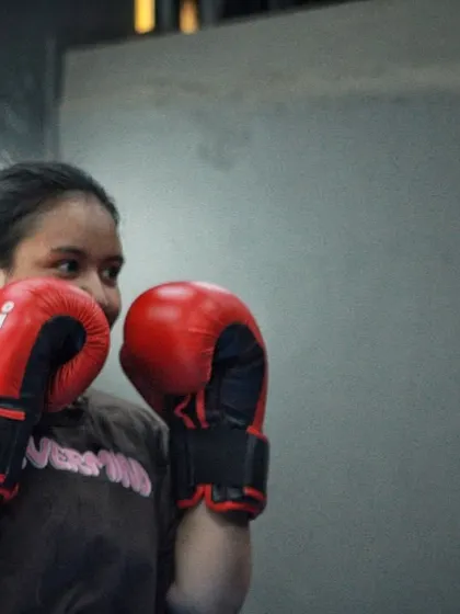 A beginner boxer holding her guard, learning the fundamentals. Every champion starts here.