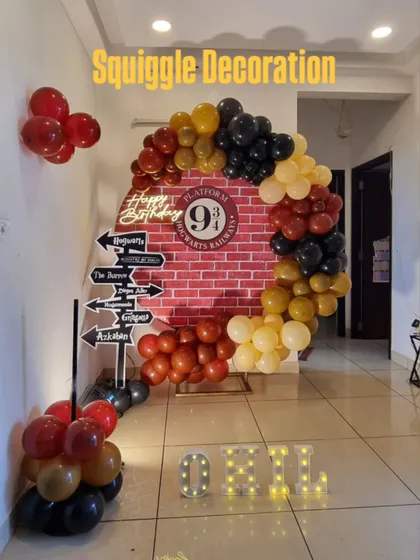 A creative Harry Potter themed photo booth with a Platform 9 3/4 brick backdrop, a circular balloon arch, and a directional sign prop.