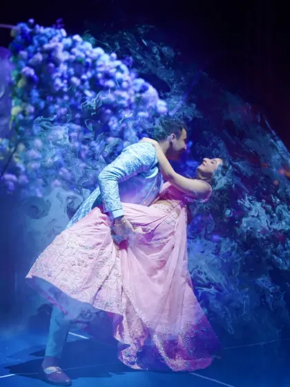 The couple strikes a dramatic pose during their dance performance against the stunning floral moon backdrop of their engagement party.